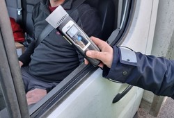 Zdjęcie przedstawiające policjanta ruchu drogowego trzymającego urządzenie do badania stanu trzeźwości.