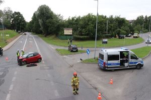 Zdjęcie przedstawiające skrzyżowanie na którym znajduje się uszkodzony pojazd oraz radiowóz.