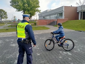 Zdjęcie przedstawiające policjanta oraz ucznia w trakcie jazdy na rowerze.