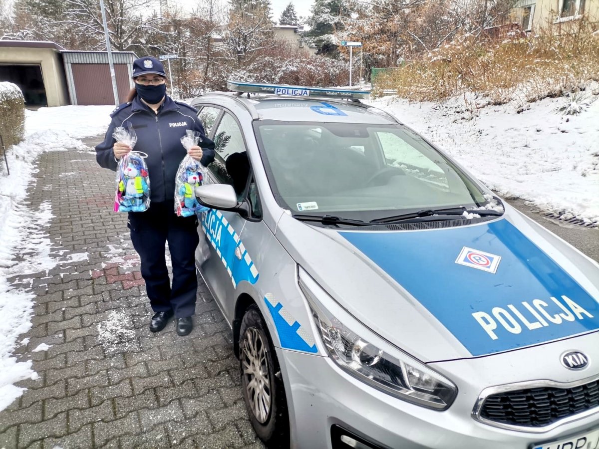 Policjanta która stoi przy radiowozie i trzyma w rękach Sznupki.