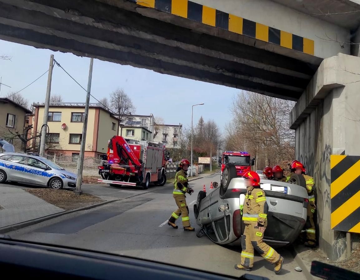 Zdjęcie uszkodzonego pojazdu oraz strażaków i radiowozu.