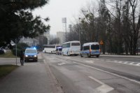 Fotografia kolorowa. Na zdjęciu widać przejazd kibiców oraz policyjne radiowozy.