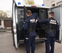 Fotografia kolorowa. Na zdjęciu widać umundurowanych policjantów oraz radiowóz.