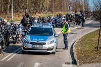 Fotografia kolorowa. Przedstawia uczestników przejazdu motocyklowego oraz policjantów zabezpieczających to wydarzenie.