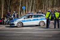 Fotografia kolorowa. Przedstawia uczestników przejazdu motocyklowego oraz policjantów zabezpieczających to wydarzenie.