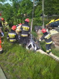 Zdjęcie kolorowe. Prace strażaków przy pojeździe mazda.