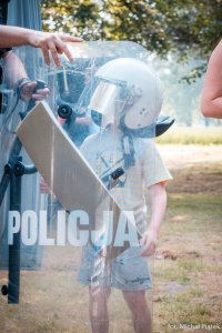 Zdjęcie kolorowe. Przedstawiające dziecko w częściowym stroju policjanta.