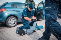 Zdjęcie kolorowe, przedstawiające festyn bezpieczeństwa, scenka zaprezentowana przez policjantów.