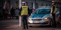 Zdjęcie kolorowe, przedstawiające policjantów zabezpieczających przemarsz.