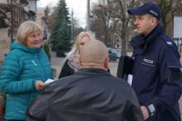 Zdjęcie kolorowe, przedstawiające dzielnicowego i pracowników socjalnych w trakcie kampanii &quot;Biała wstążka&quot;.