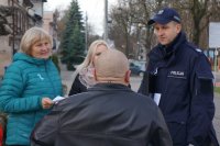 Zdjęcie kolorowe, przedstawiające dzielnicowego i pracowników socjalnych w trakcie kampanii &quot;Biała wstążka&quot;.