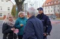 Zdjęcie kolorowe, przedstawiające dzielnicowego i pracowników socjalnych w trakcie kampanii &quot;Biała wstążka&quot;.