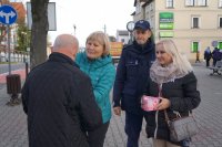 Zdjęcie kolorowe, przedstawiające dzielnicowego i pracowników socjalnych w trakcie kampanii &quot;Biała wstążka&quot;.