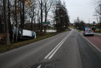 Zdjęcie kolorowe, przedstawiające policjanta i uszkodzony pojazd ford.