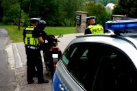 Zdjęcie kolorowe, przedstawiającego policjantów, którzy kontrolują motorowerzystę.