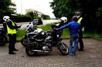 Zdjęcie kolorowe, przedstawiające policjantów pełniących służbę na motocyklach i motorowerzystę.