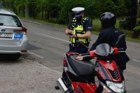 Zdjęcie kolorowe, przedstawiające policjantów i motorowerzystę.