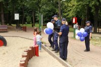 Zdjęcie kolorowe, przedstawiające policjantów i dzieci w parku.