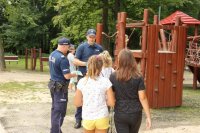 Zdjęcie kolorowe, przedstawiające policjantów i dzieci w parku.