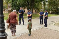 Zdjęcie kolorowe, przedstawiające policjantów i dzieci w parku.