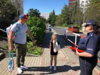 Zdjęcie kolorowe, przedstawiające policjantów i dzieci przed szkołami.