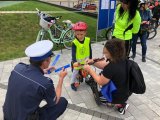 Zdjęcie kolorowe, przedstawiające policjanta i osoby uczestniczące w rajdzie rowerowym.