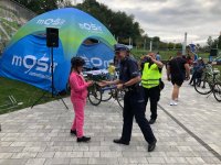 Zdjęcie kolorowe, przedstawiające policjanta i osoby uczestniczące w rajdzie rowerowym.