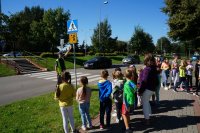 Zdjęcie kolorowe, przedstawiające policjanta ruchu drogowego oraz dzieci uczestniczące w prelekcjach.