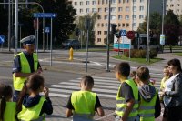 Zdjęcie kolorowe przedstawiające policjanta ruchu drogowego oraz uczestników prelekcji.