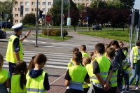 Zdjęcie kolorowe przedstawiające policjanta ruchu drogowego oraz uczestników prelekcji.