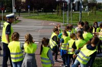 Zdjęcie kolorowe, przedstawiające policjanta ruchu drogowego i dzieci.