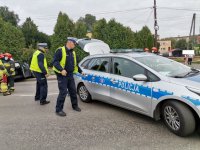 Zdjęcie kolorowe, przedstawiające policjantów ruchu drogowego i miejsce zdarzenia drogowego.