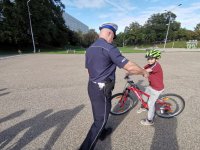 Zdjęcie kolorowe, przedstawiające policjanta ruchu drogowego i dzieci zdające kartę rowerową.