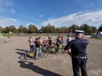 Zdjęcie kolorowe, przedstawiające policjanta ruchu drogowego i dzieci zdające kartę rowerową.