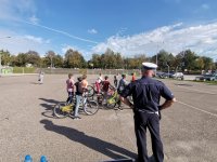 Zdjęcie kolorowe, przedstawiające policjanta ruchu drogowego i dzieci zdające kartę rowerową.