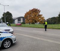 Zdjęcie kolorowe, przedstawiające policjanta ruchu drogowego w trakcie kontroli drogowej.