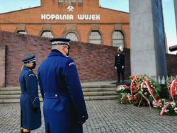 Zdjęcie kolorowe, przedstawiające przedstawicieli policji składających kwiaty przed pomnikiem.