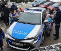 Zdjęcie przedstawiające dzieci oglądające radiowóz policyjny.