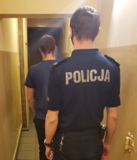 Zdjęcie kolorowe, przedstawiające policjanta oraz osobę zatrzymaną.