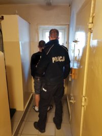 Zdjęcie kolorowe, przedstawiające policjanta oraz osobę zatrzymaną.