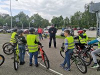 Zdjęcie kolorowe, przedstawiające osoby przystępujące do karty rowerowej oraz policanta.