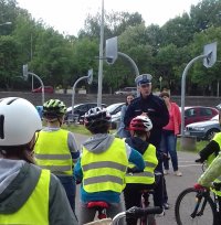 Zdjęcie kolorowe, przedstawiające osoby przystępujące do karty rowerowej oraz policjant, który omawia zasady na torze .