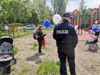 Zdjęcie kolorowe, przedstawiające policjantkę na placu zabaw oraz dzieci.