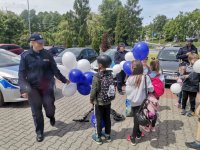 Zdjęcie kolorowe, przedstawiające dzieci oraz policjantów w trakcie pogadanki.