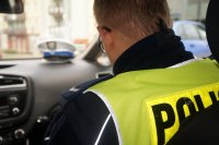 Zdjęcie kolorowe, przedstawiające policjanta w radiowozie.