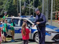 Zdjęcie przedstawiające dzieci na spotakniu oraz policjnata rozdającego odblaski.