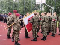 Zdjęcie przedstawiające sztandar i uczniów klas mundurowych.