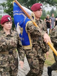 Zdjęcie przedstawiające sztandar i uczniów którzy go niosą.