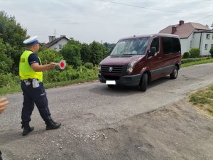 Zdjęcie kolorowe, przedstawiające policjanta ruchu drogowego oraz zatrzymany pojazd.