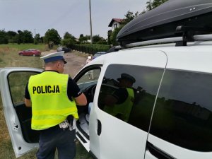 Zdjęcie kolorowe, przedstawiające policjanta ruchu drogowego oraz zatrzymany pojazd.